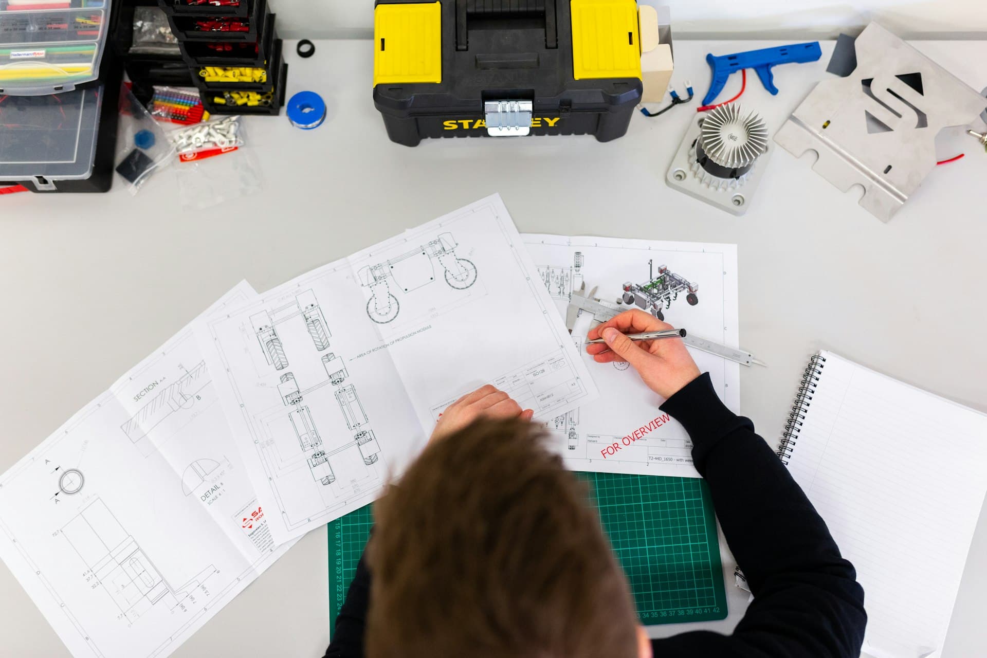 An engineer marking up technical drawings at a workbench.