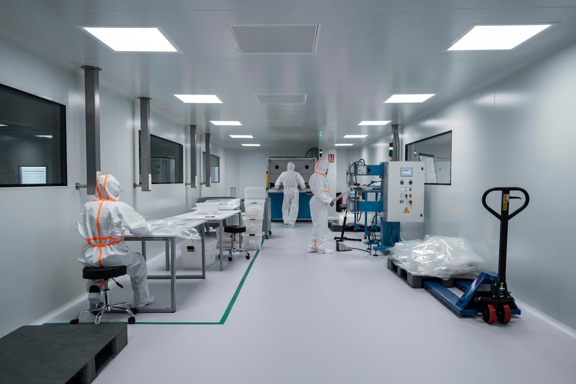 Engineers in protective suits working in a medical device cleanroom.